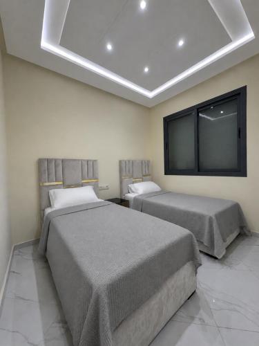 a bedroom with two beds and a flat screen tv at Résidence Maryam in Nador