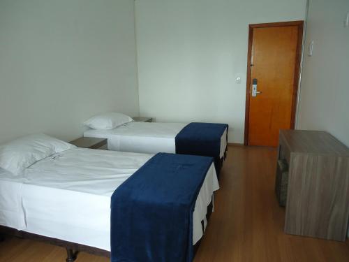 a room with two beds and a wooden door at Hotel St. Daniel in Guarulhos