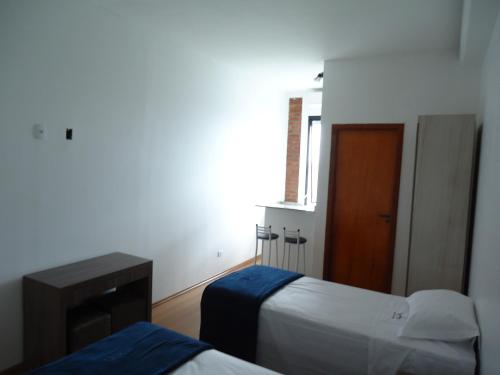 a bedroom with two beds and a table and a window at Hotel St. Daniel in Guarulhos