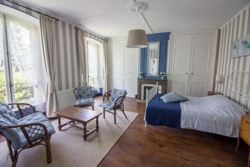 a bedroom with a bed and chairs and a table at Domaine des Lilas in Saint-Germain-Lembron