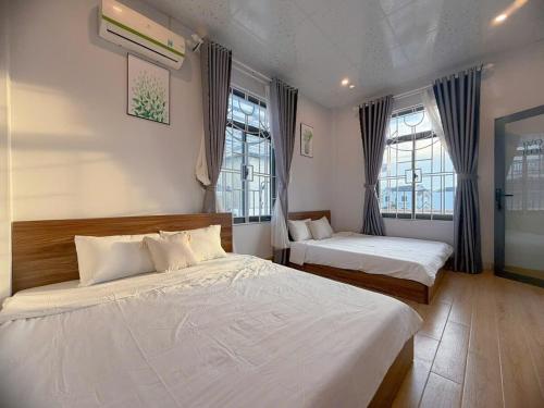 a bedroom with two beds and two windows at Arden Reserve Villa in Binh Thai