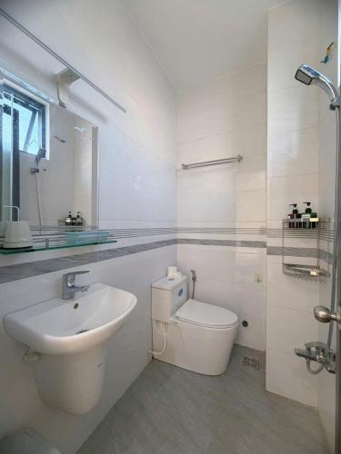 a white bathroom with a sink and a toilet at Arden Reserve Villa in Binh Thai