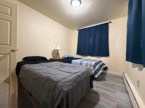 two beds in a room with blue curtains at Cozy Place in Anchorage