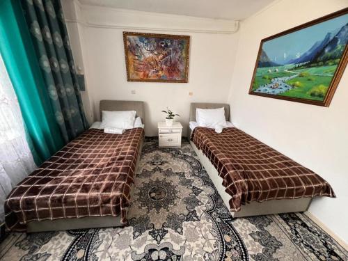 a bedroom with two beds and a rug at AJO Guesthouse in Naryn