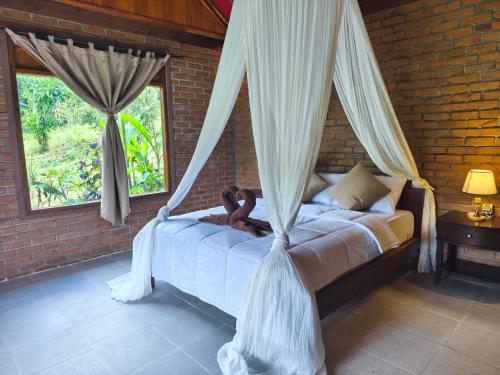 a woman sitting on a bed in a bedroom at Tuka Cabins in Jatiluwih