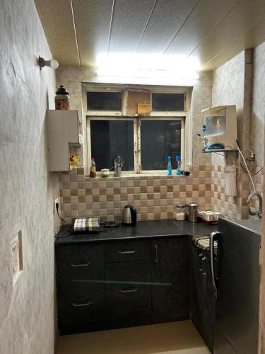 a small kitchen with black cabinets and a window at RADHEY RADHEY stays in Vrindāvan