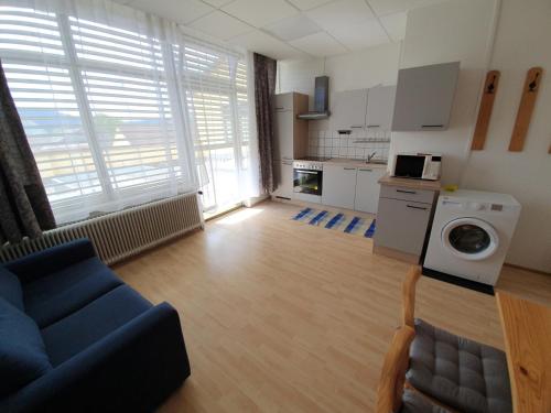 a living room with a blue couch and a kitchen at Grössingblick in Zeltweg