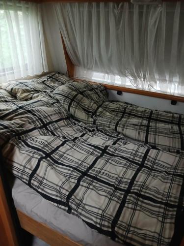 a bed with a black and white plaid blanket at Túrkeve Lakó in Túrkeve