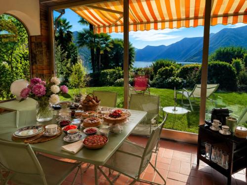 a table with food and a view of the mountains at Lake View Palm Garden in Lugano