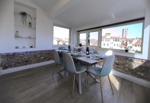 a dining room with a table and chairs and windows at Attico di Cesare Luxury Piazza Anfiteatro Lucca in Lucca