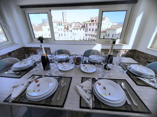 a table with white plates and wine glasses on it at Attico di Cesare Luxury Piazza Anfiteatro Lucca in Lucca