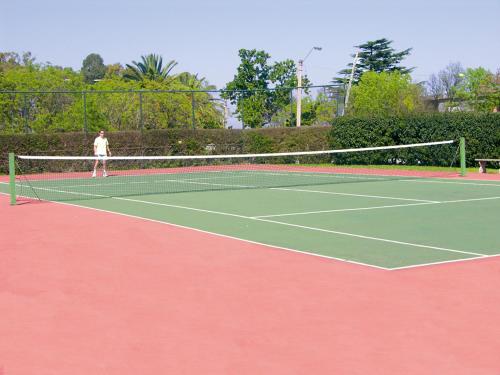 a man is standing on a tennis court at El Mirador Hotel & Spa in Colonia del Sacramento