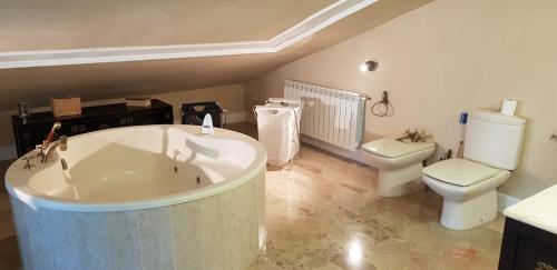 a bathroom with a large tub and a toilet at Espaciosa villa con piscina, ideal para relajarse en familia in Los Hueros