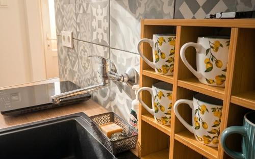 a kitchen with a sink and a shelf with cups at Mekcsey Udvar in Eger