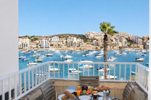 a balcony with a view of a harbor with boats at Blue Harbour 2 bedroom Seafront Apartments with large terrace with spectacular sea views - by Getawaysmalta in St. Paul's Bay