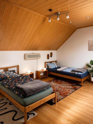 two beds in a room with a wooden ceiling at Monteurzimmer-Graf in Nidda