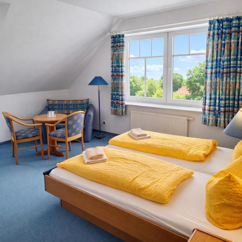 two beds in a room with a table and a window at Sporthotel Middelpunkt in Aurich
