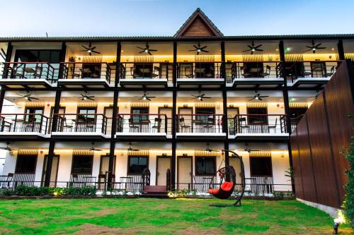 an apartment building with a hammock in the courtyard at Hotel De Nara-SHA Extra Plus in Chiang Mai