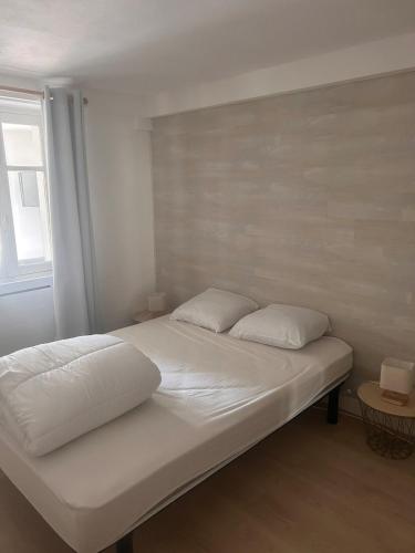 a bed with white sheets and pillows in a room at À 100m de l ocean in Longeville-sur-Mer
