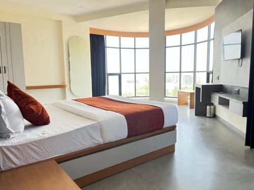 a bedroom with a large bed with a large window at Hotel Sun Park Vadodara in Vadodara