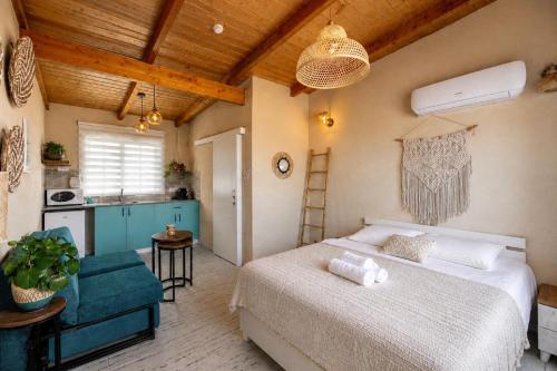 a bedroom with a large bed and a kitchen at בריאה אירוח בטבע in Sha'al