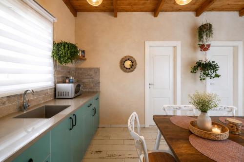 a kitchen with a sink and a table with chairs at בריאה אירוח בטבע in Sha'al