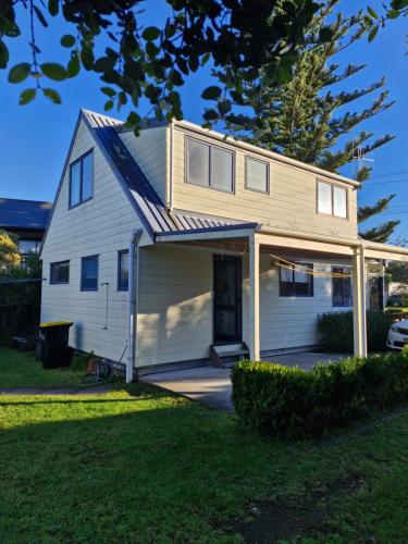 a small white house with a garage at Estuary Hideaway in Whangamata