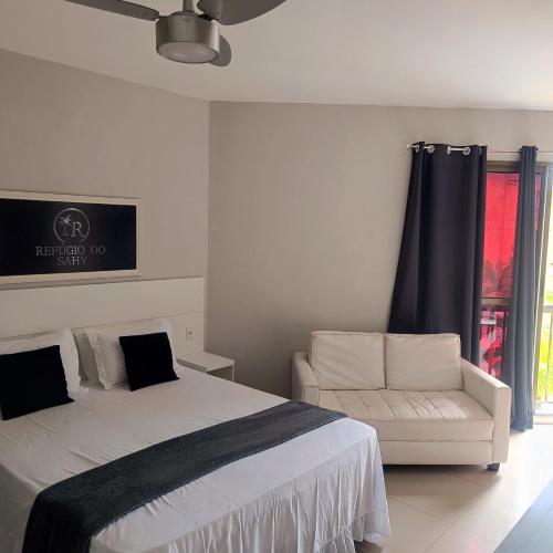 a bedroom with a bed and a couch and a window at Loft no Refúgio do Sahy in Mangaratiba
