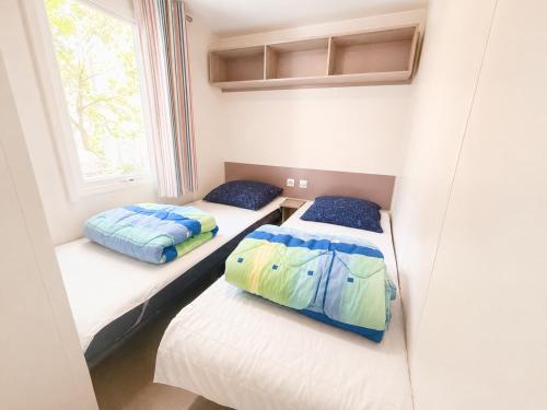 two beds in a small room with a window at Greenchalets Roquebrune Sur Argens in Roquebrune-sur-Argens