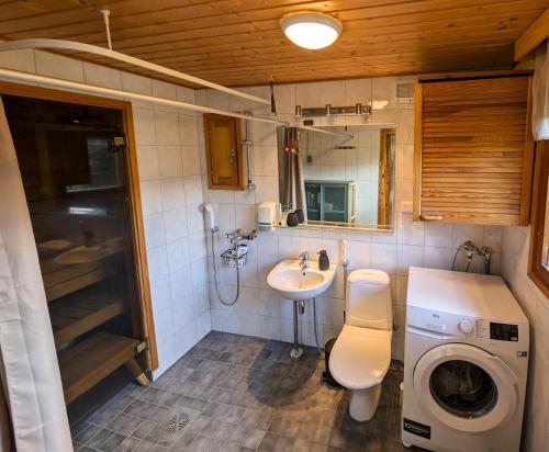 ein Badezimmer mit Toilette, Waschbecken und Waschmaschine in der Unterkunft Whispering Woods Cabin in Porvoo