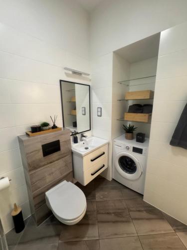 a bathroom with a toilet and a sink and a washing machine at Apartament Noniewicza 95 in Suwałki