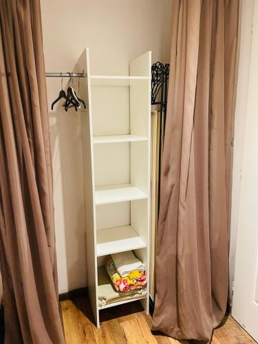 a white book shelf next to a curtain at Studio Cosy in Saint-Juéry