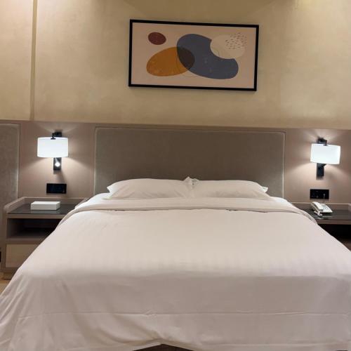 a bedroom with a large white bed with two tables at Mandarin Alshamal Hotel Apartments in Riyadh