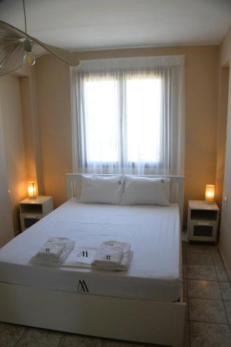 a bedroom with a large white bed with a window at Mellonia in Nikiti