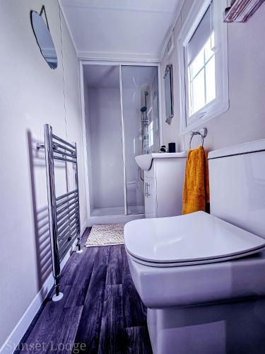 a white bathroom with a toilet and a window at Sunset lodge 32 in West Thirston