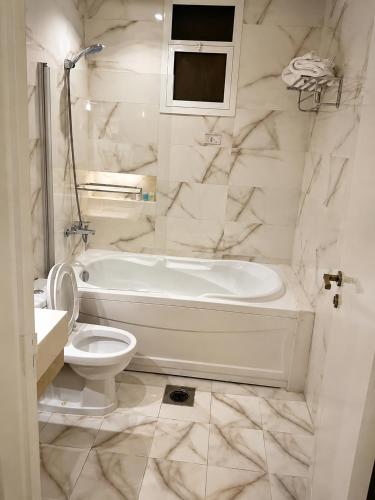 a white bathroom with a tub and a toilet at الفرسان للشقق المخدومه in Al Kharj