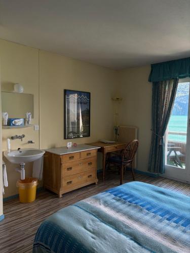 a bedroom with a bed and a desk and a sink at Seehotel Bären in Brienz