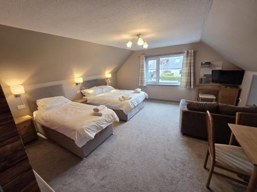 a hotel room with two beds and a couch at Sanderlay Guest House in Kirkwall