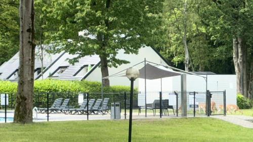 a park with two benches and a tent in the grass at Hengelhoef Acacia 3 in Drijhoeven