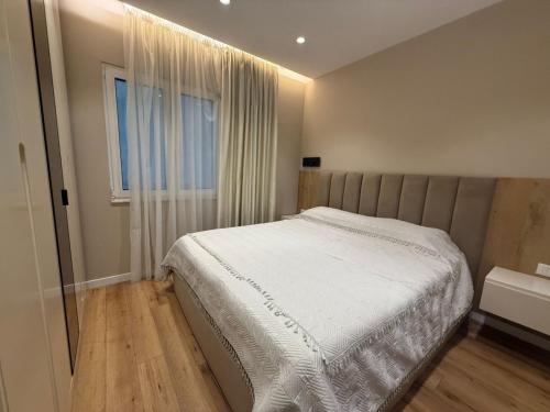 a bedroom with a white bed and a window at Tirana Lake Bliss Apartment in Sauk