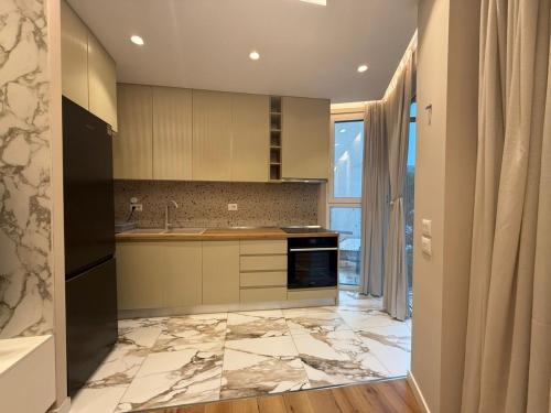a kitchen with marble flooring and a large window at Tirana Lake Bliss Apartment in Sauk