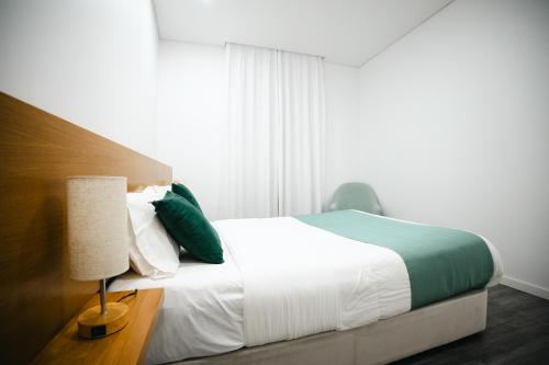 a bedroom with a bed and a lamp and a window at Casa das Ondas in Ribeira Grande