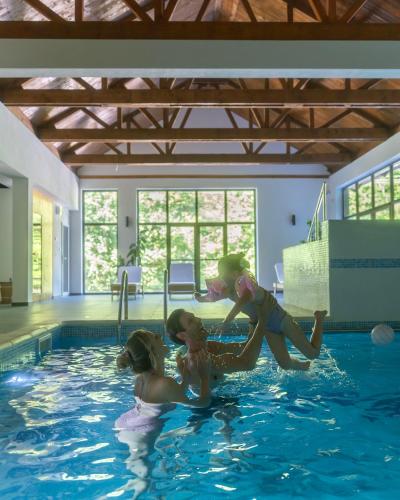 three girls playing in a swimming pool at Lisine Lepo Mesto Guesthouse & Spa in Strmosten