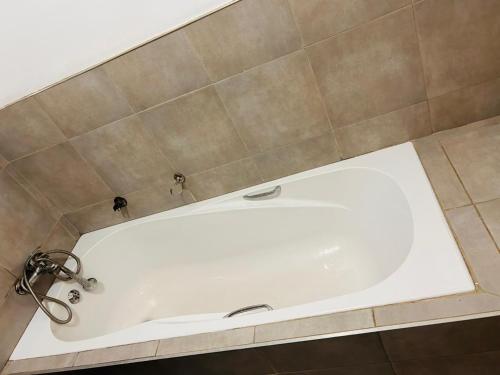 a white tub in a bathroom with a tiled wall at MandA Cozy GuestHouse in Middelburg