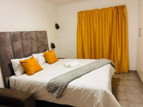 a bedroom with a large bed with orange and white pillows at MandA Cozy GuestHouse in Middelburg