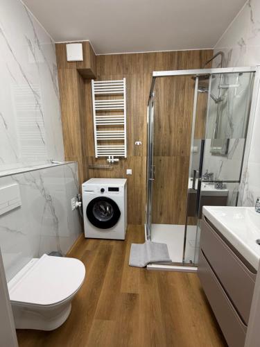 a bathroom with a shower toilet and a washing machine at MG Apartament City Park in Szczecinek