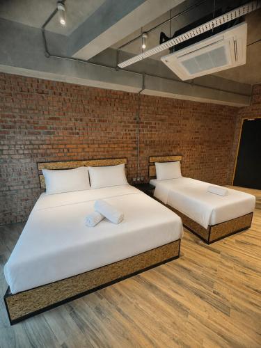 two beds in a room with a brick wall at Brick Box Family Hotel Ipoh in Ipoh