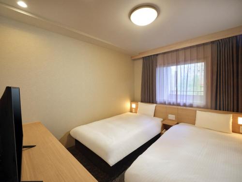 a hotel room with two beds and a window at Dormy Inn Hiroshima in Hiroshima