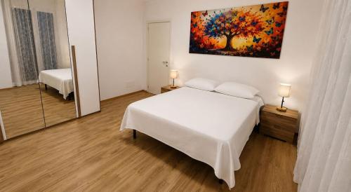 a bedroom with a white bed and a painting on the wall at sunset suite con terrazza e barbecue in Imperia