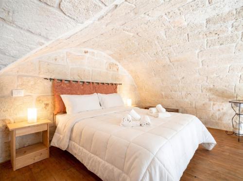 a bedroom with a white bed in a brick wall at Casa Tino - Retreat by the Sea and History in Polignano a Mare
